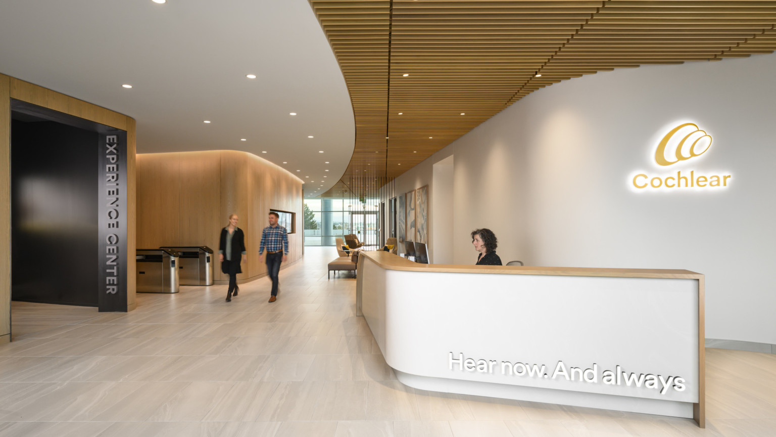 Cochlear North American Headquarters entrance with white reception desk in front of backlit logo with wood ceiling accents
