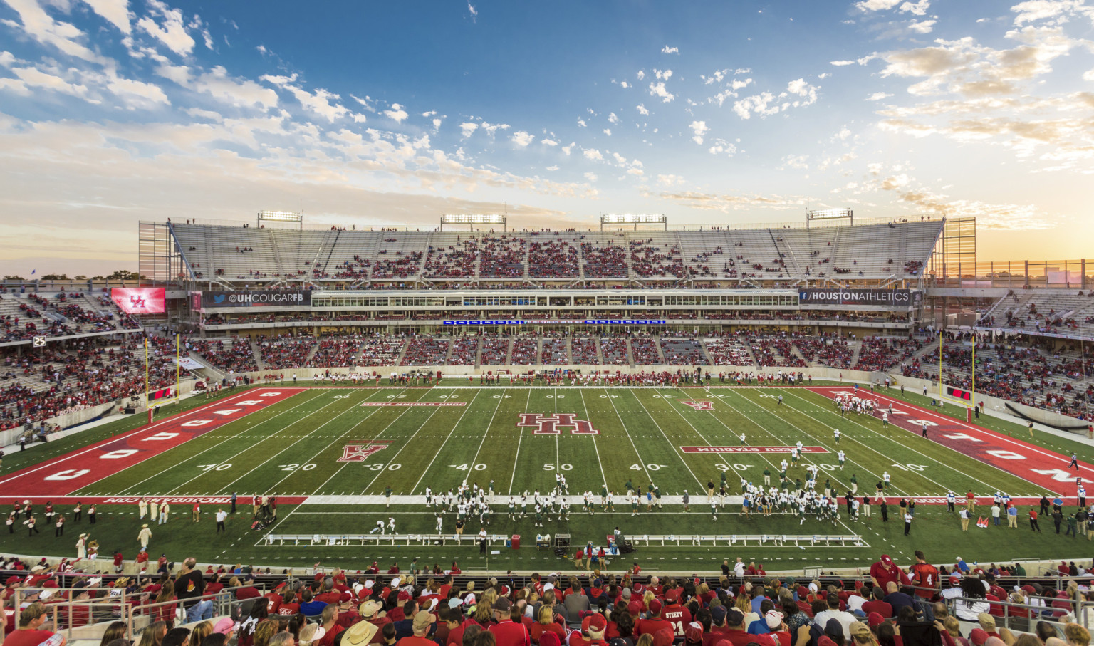 View of football field from upper deck seating at 50 yard line. Red end zones with Houston Cougars written across them View of football field from upper deck seating at 50 yard line. Red end zones with Houston Cougars written across them