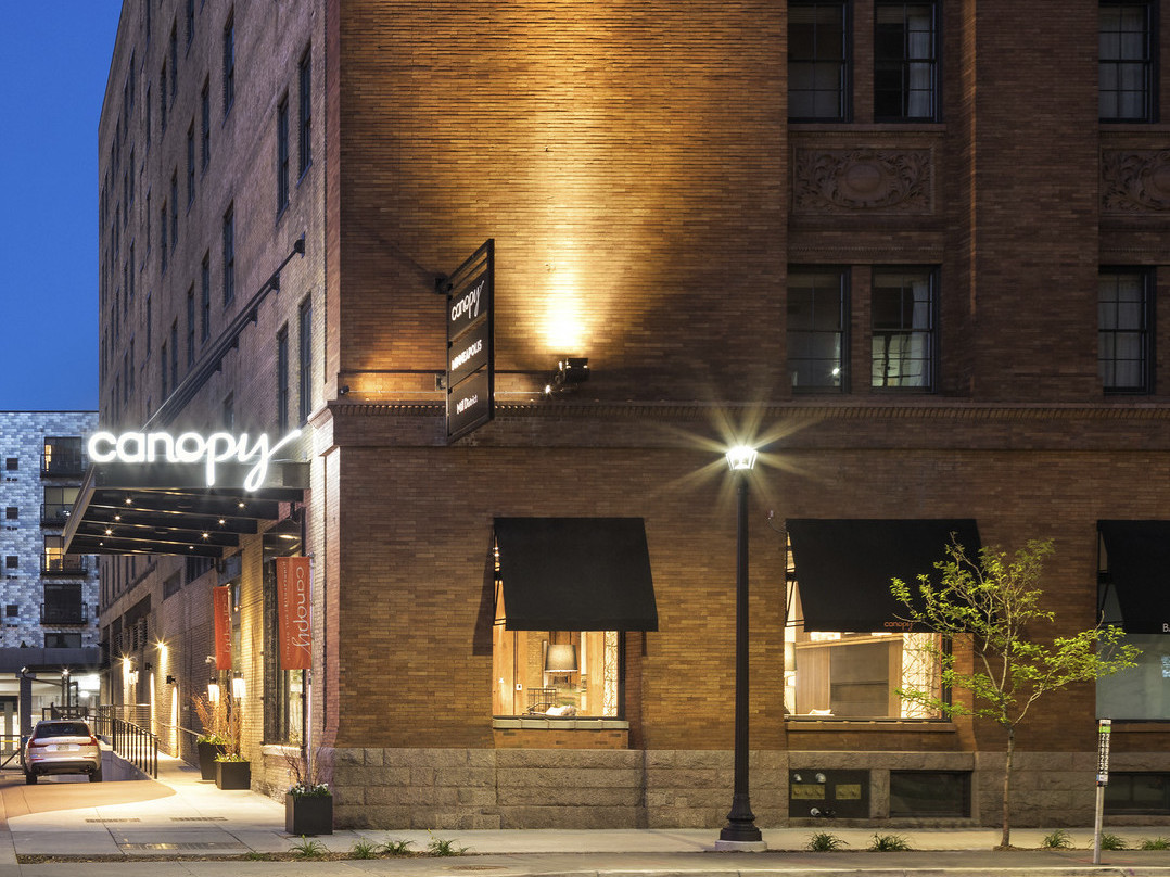 Canopy by Hilton Minneapolis Mill District sign illuminated over door of brick building with black awnings over windows