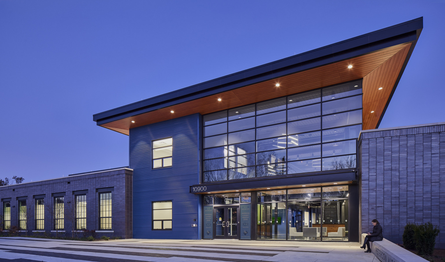 exterior of a doubleheight modern architecture glass atrium with a wood canopy overhang at Peterson Middle School