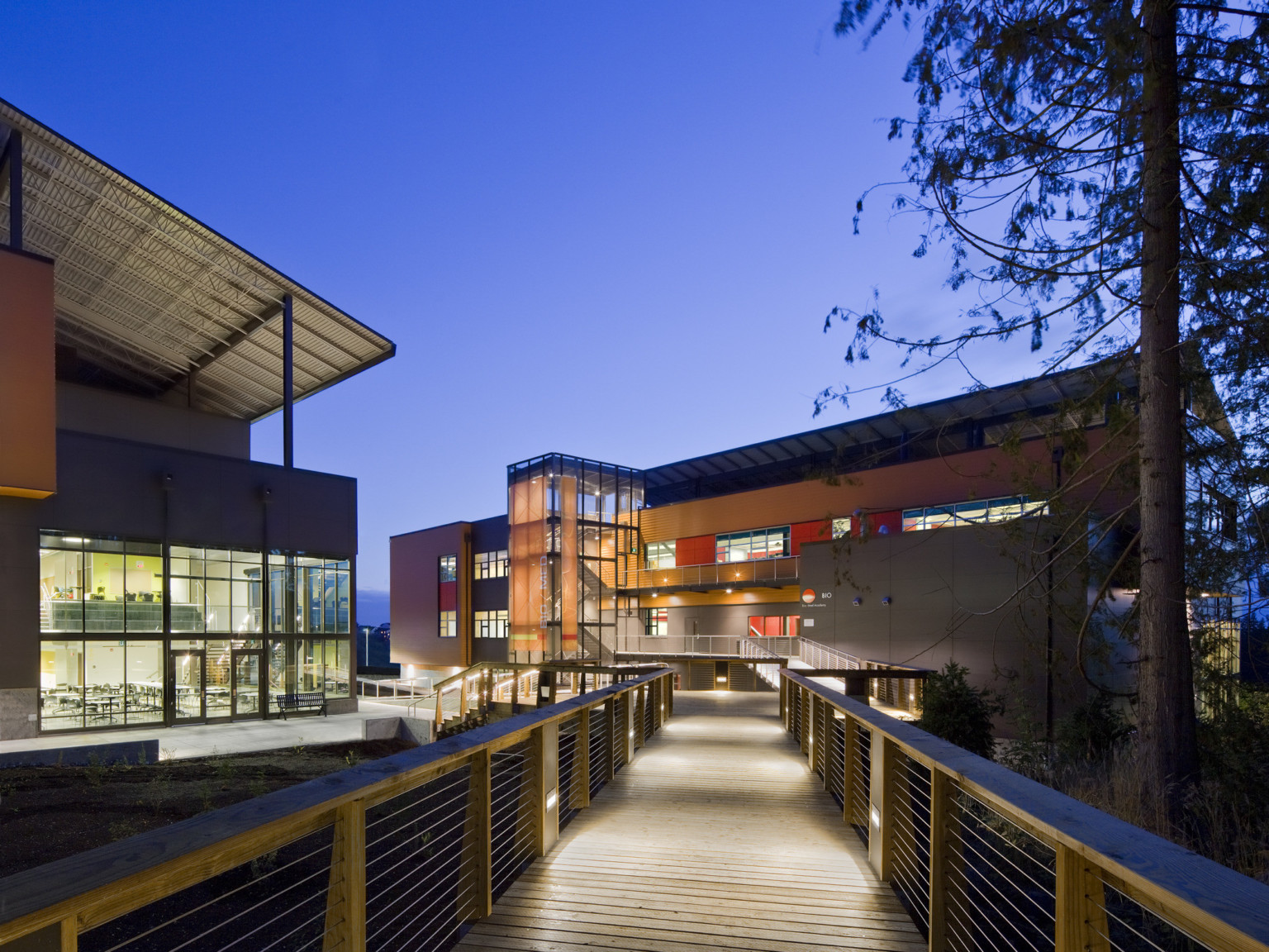 Marysville Getchell High School pedestrian bridge crosses to 2 buildings. Glass entrances and orange accents on each building