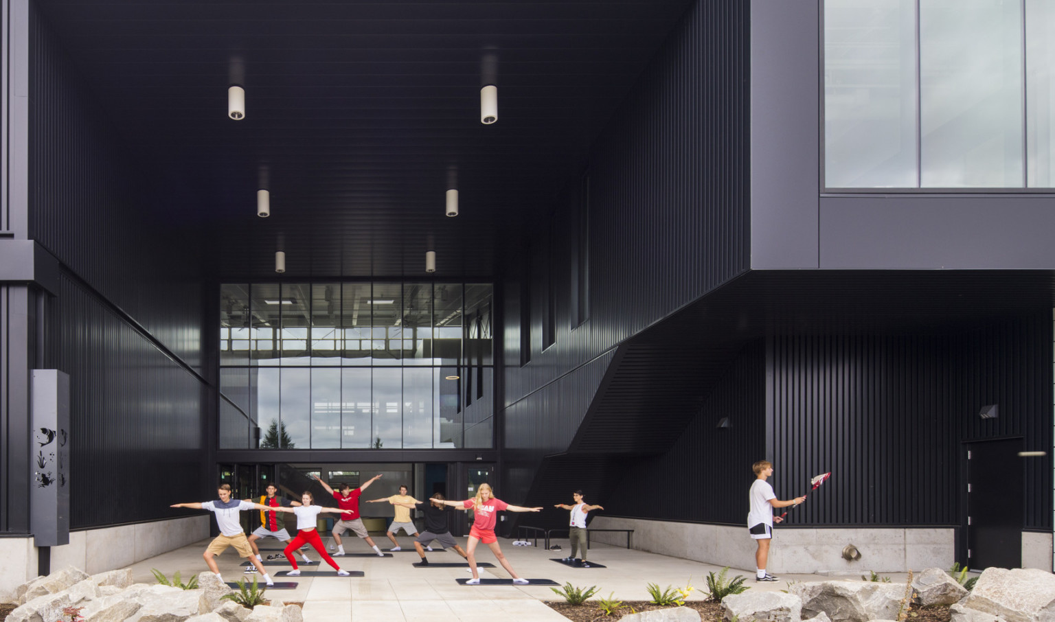 Exterior view, atrium is recess and patio is covered. Right, the building extends in a black tunnel with large window at end Exterior view, atrium is recess and patio is covered. Right, the building extends in a black tunnel with large window at end