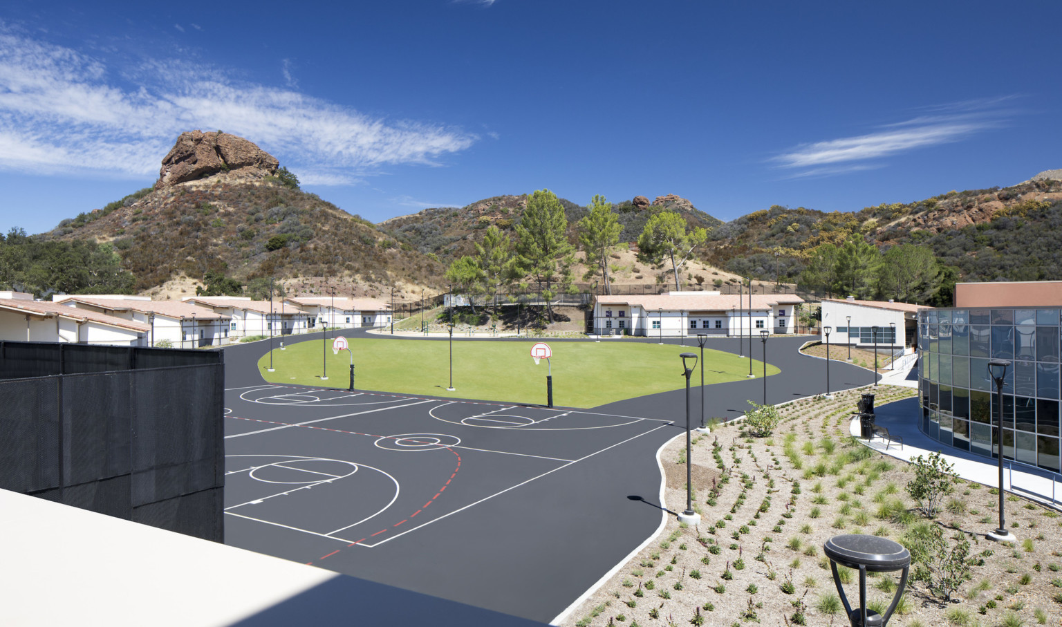 Rendering of a courtyard with basketball courts and a grassy area. Buildings along the back and right side. Hills beyond Rendering of a courtyard with basketball courts and a grassy area. Buildings along the back and right side. Hills beyond