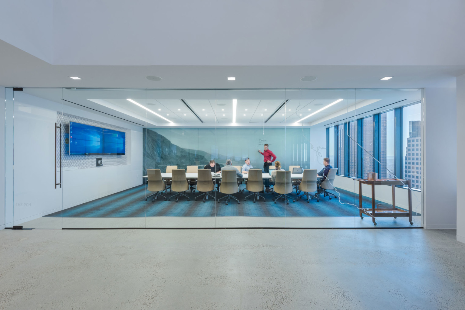 DLR Group's Los Angeles office with glass walled conference room, large windows, wall mural, and screen at end of long table