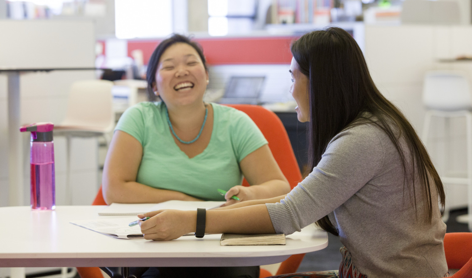 two women sitting at a table laughing two women sitting at a table laughing