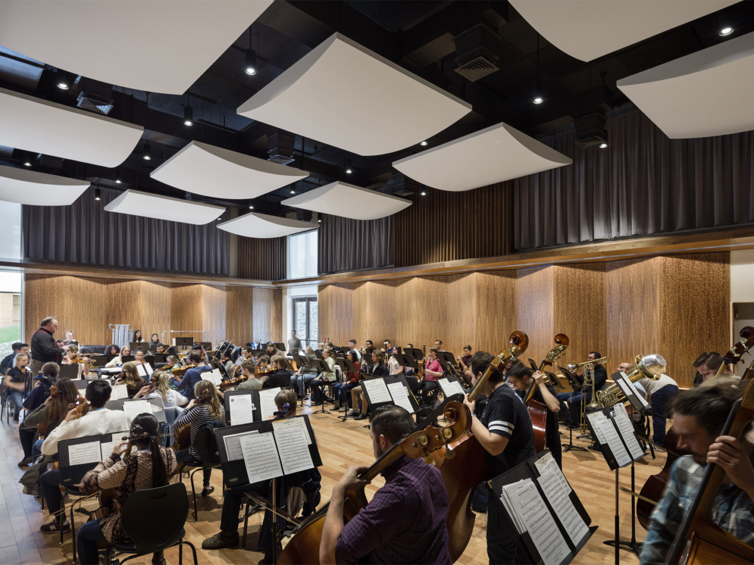 Student musicians rehearsing in studio with angled wood panels on the walls and white acoustical sound panels on the ceiling