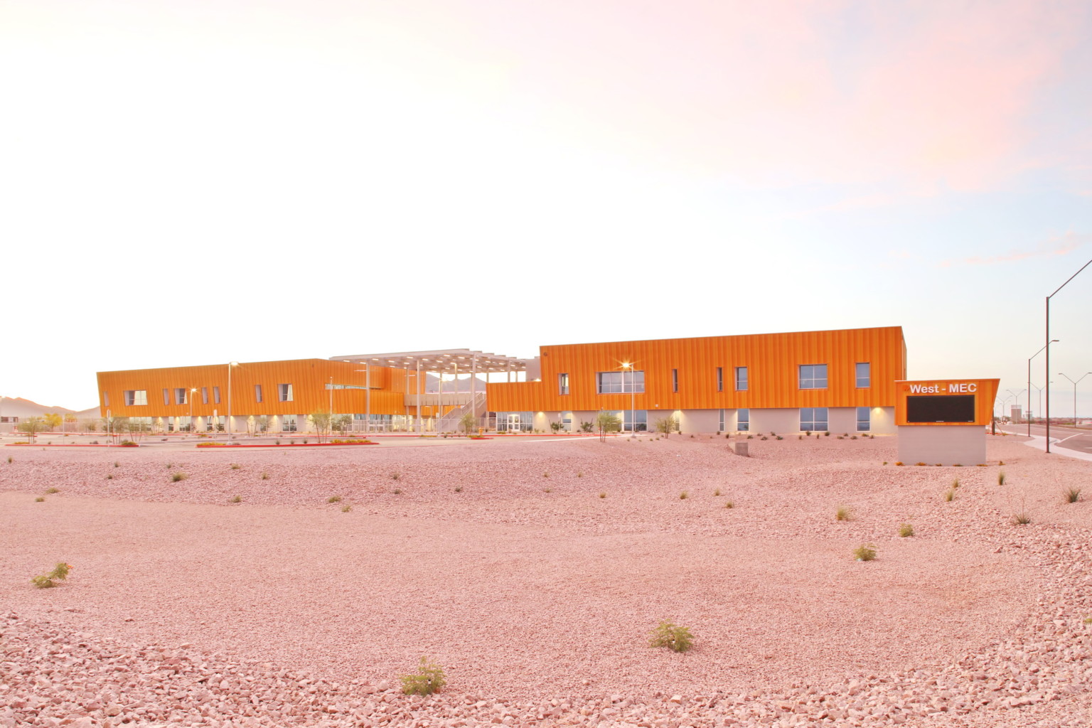 exterior view of a long orange building, designed to be net positive in energy creation in Arizona