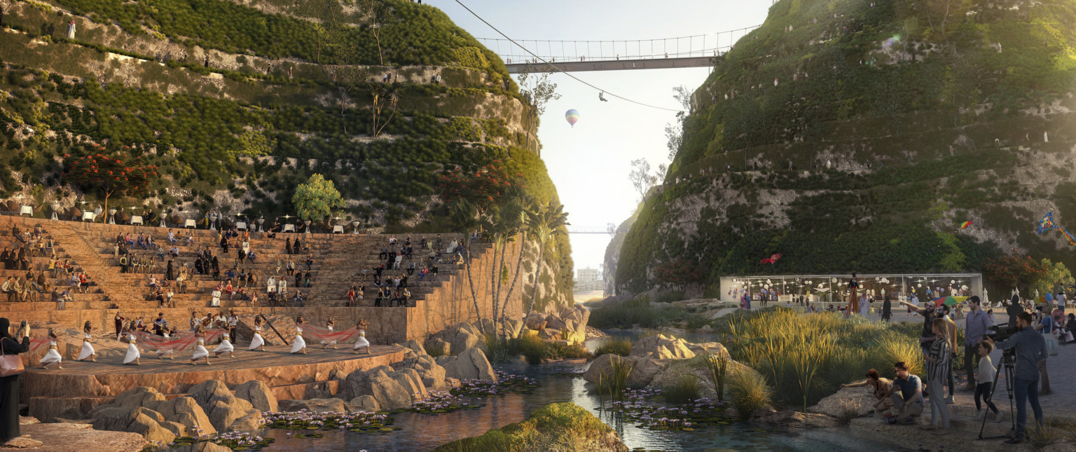 Outdoor theater with rounded stage, seats built into the left large grassy rock hill with pass and bridge connecting above