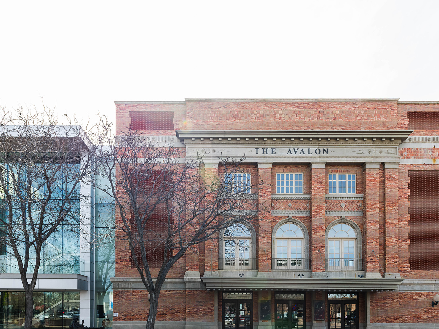 Brick and stone low rise building with arched windowed, inset columns, and adjoining glass and steel addition of same height Brick and stone low rise building with arched windowed, inset columns, and adjoining glass and steel addition of same height