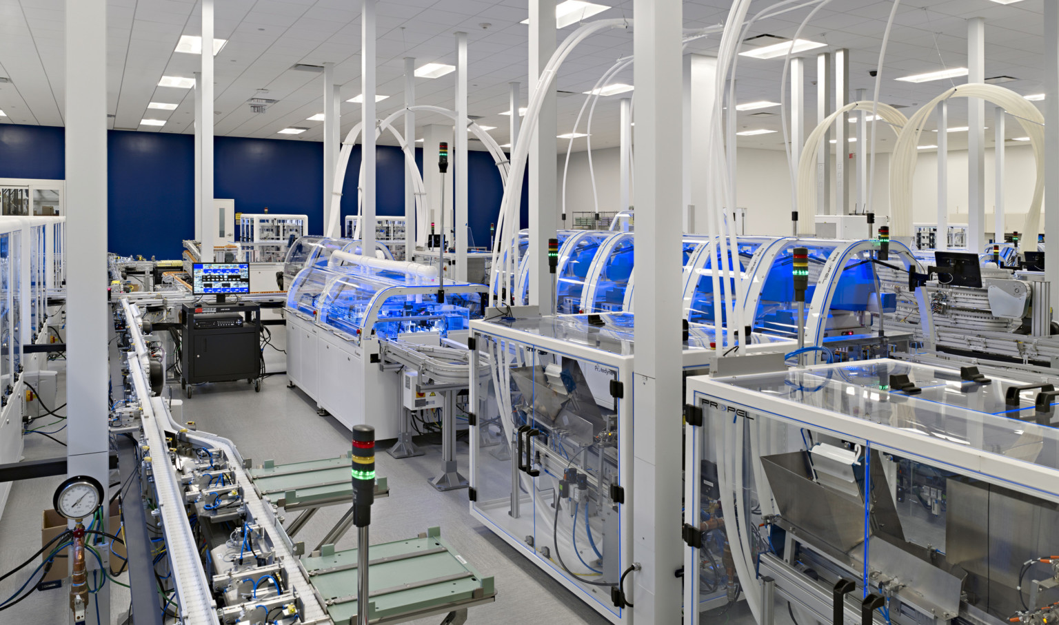 lab environment with rows of clear glass electronic manufacturing cubes with plastic tube systems connecting to the ceiling