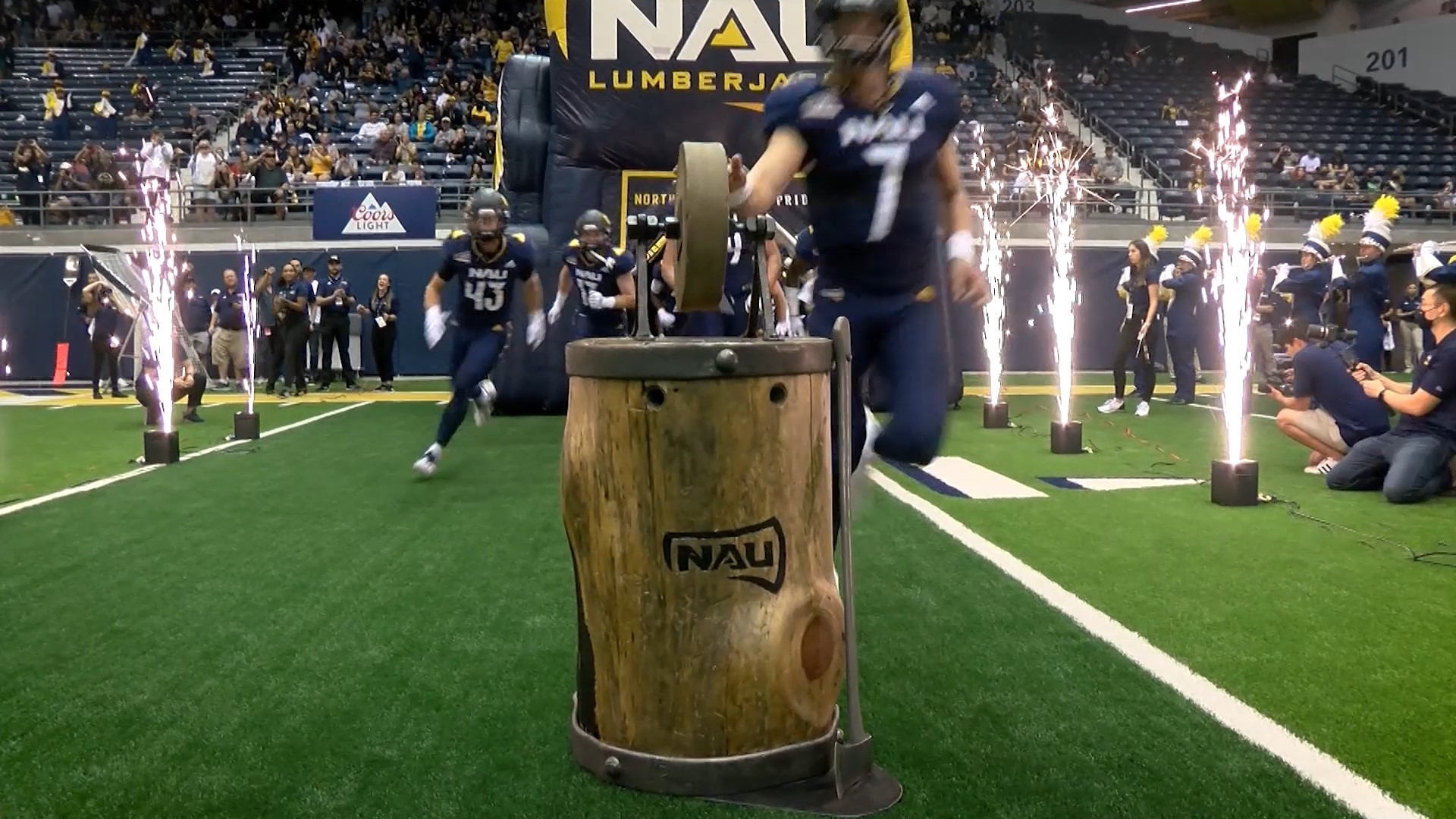 Northern Arizona University football team running out onto the field touching the iconic honing stone.