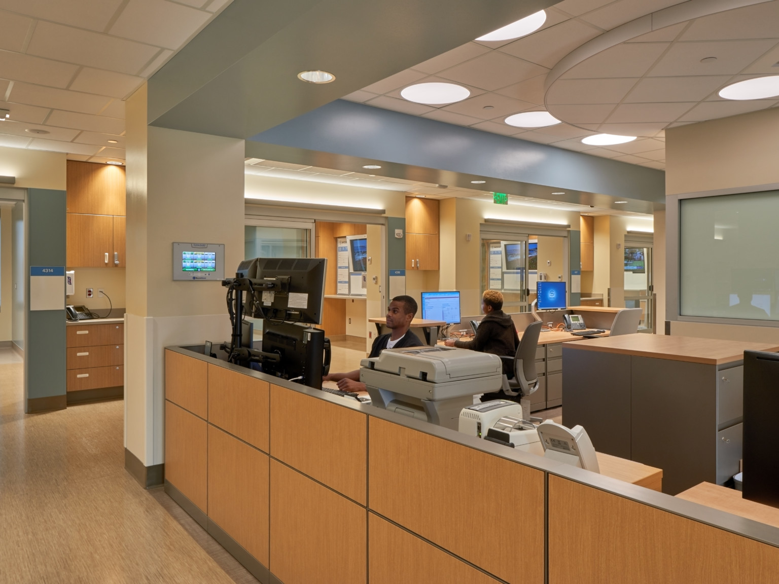 A wood panel desk in Swedish Issaquah Medical Center framed by the wall section and drop ceiling accent in corner workstation