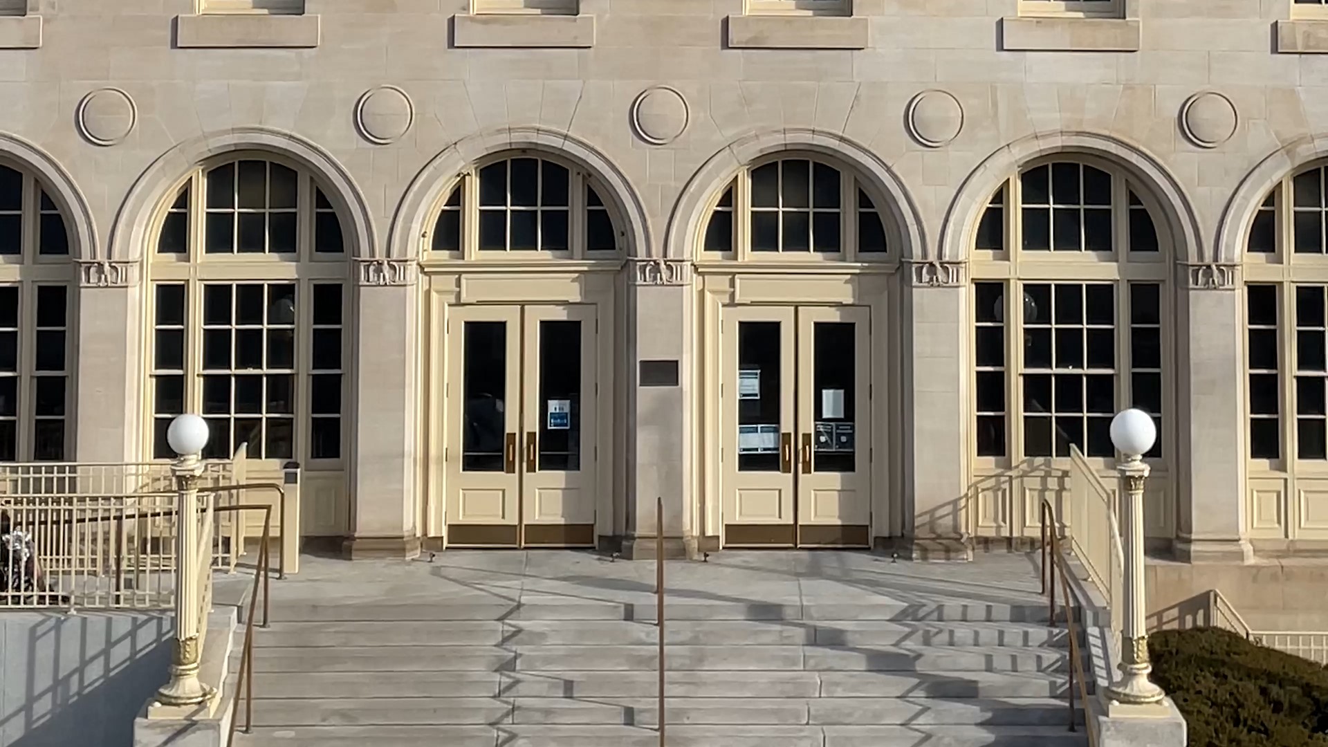 Front doors of a federal building, showing classical design with stone arches and steps leading up to the doors