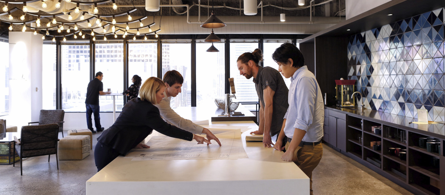 team collaborating over design drawings at an office space in Los Angeles team collaborating over design drawings at an office space in Los Angeles