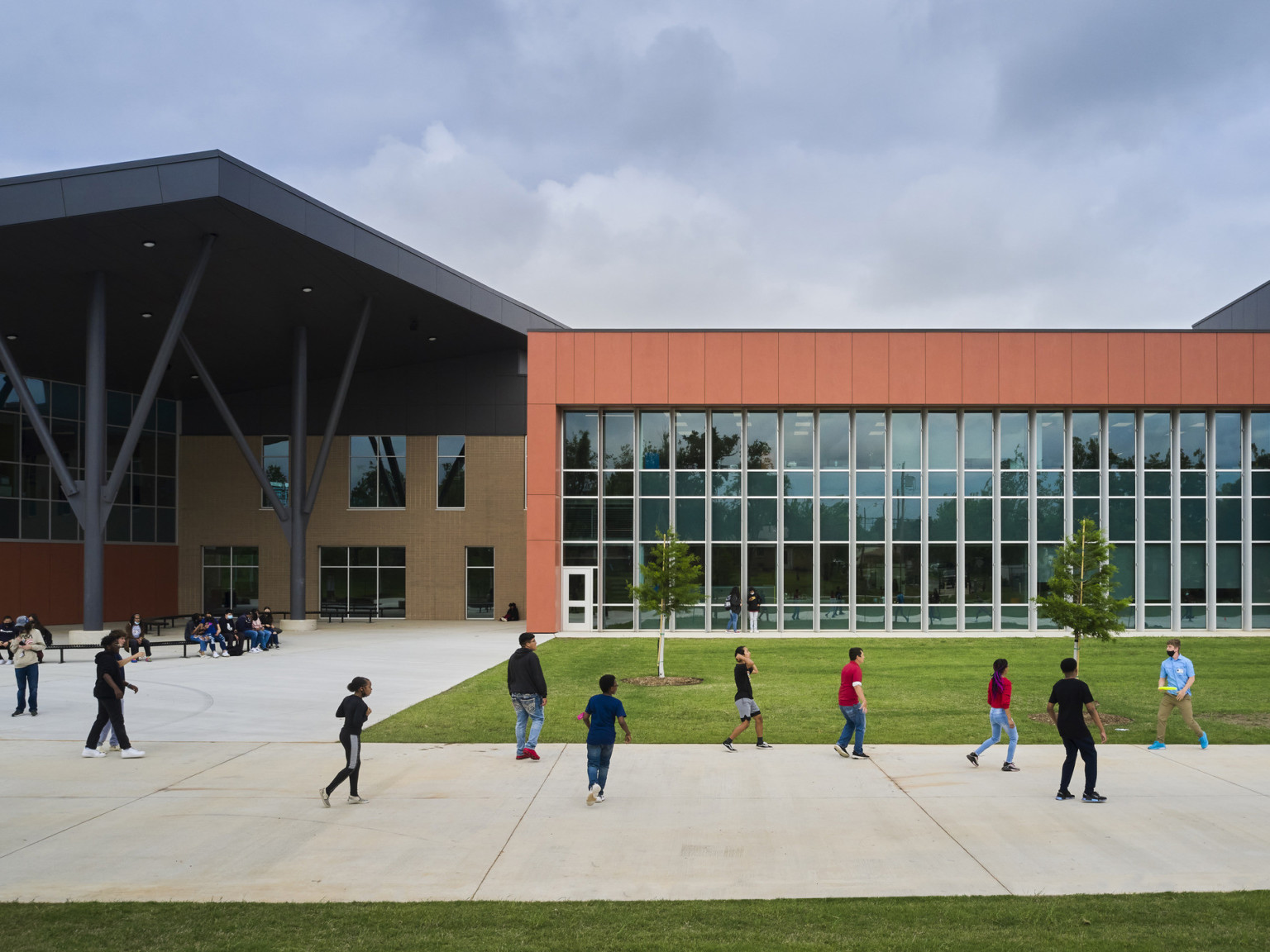 James L. Capps Middle School exterior with angled black shelter brick building. Orange wrap facade over double height glass