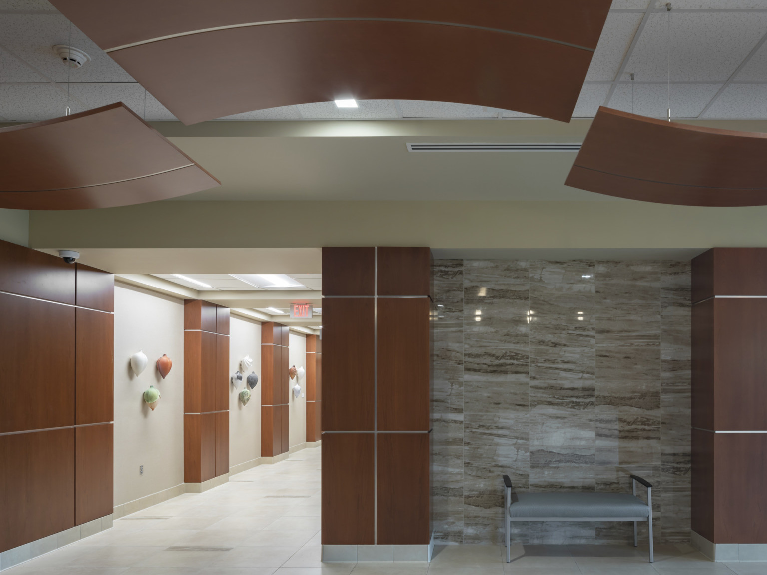 Corner intersection of hallway with wood accents on wall and matching acoustical panels. Abstract wall panels on left wall