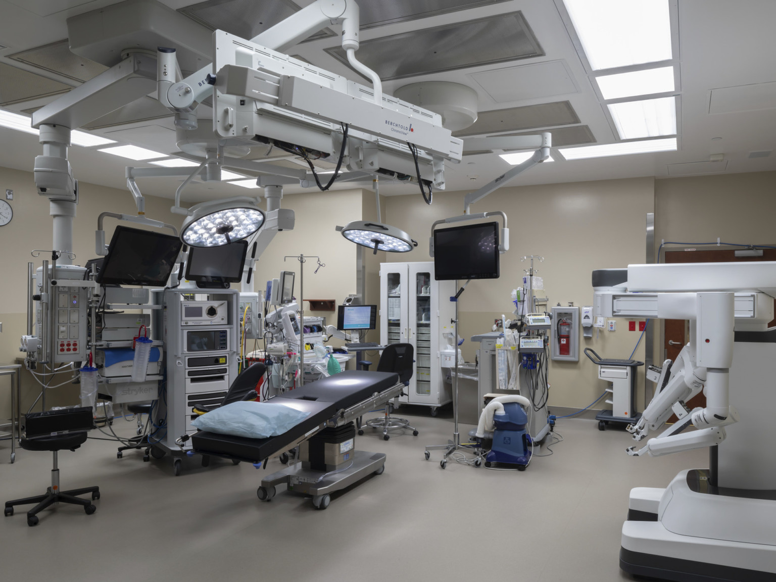 Spacious operating room interior with equipment along walls and suspended above