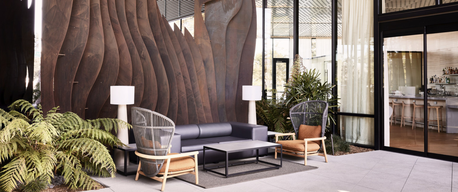 A two-story weathered steel form emerges from the ground creating intrigue within the central breezeway activating the public space.