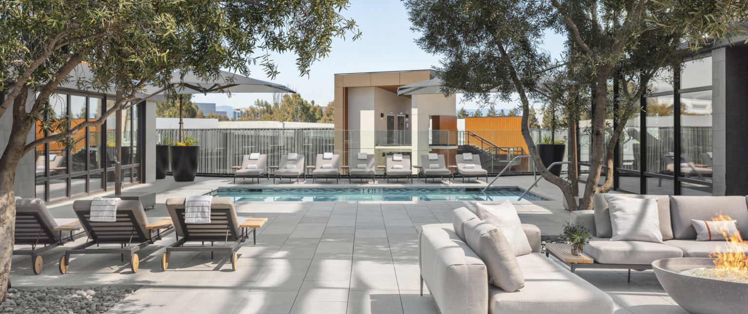 Lush landscaping, lounge seating, and firepit surround heated outdoor pool.