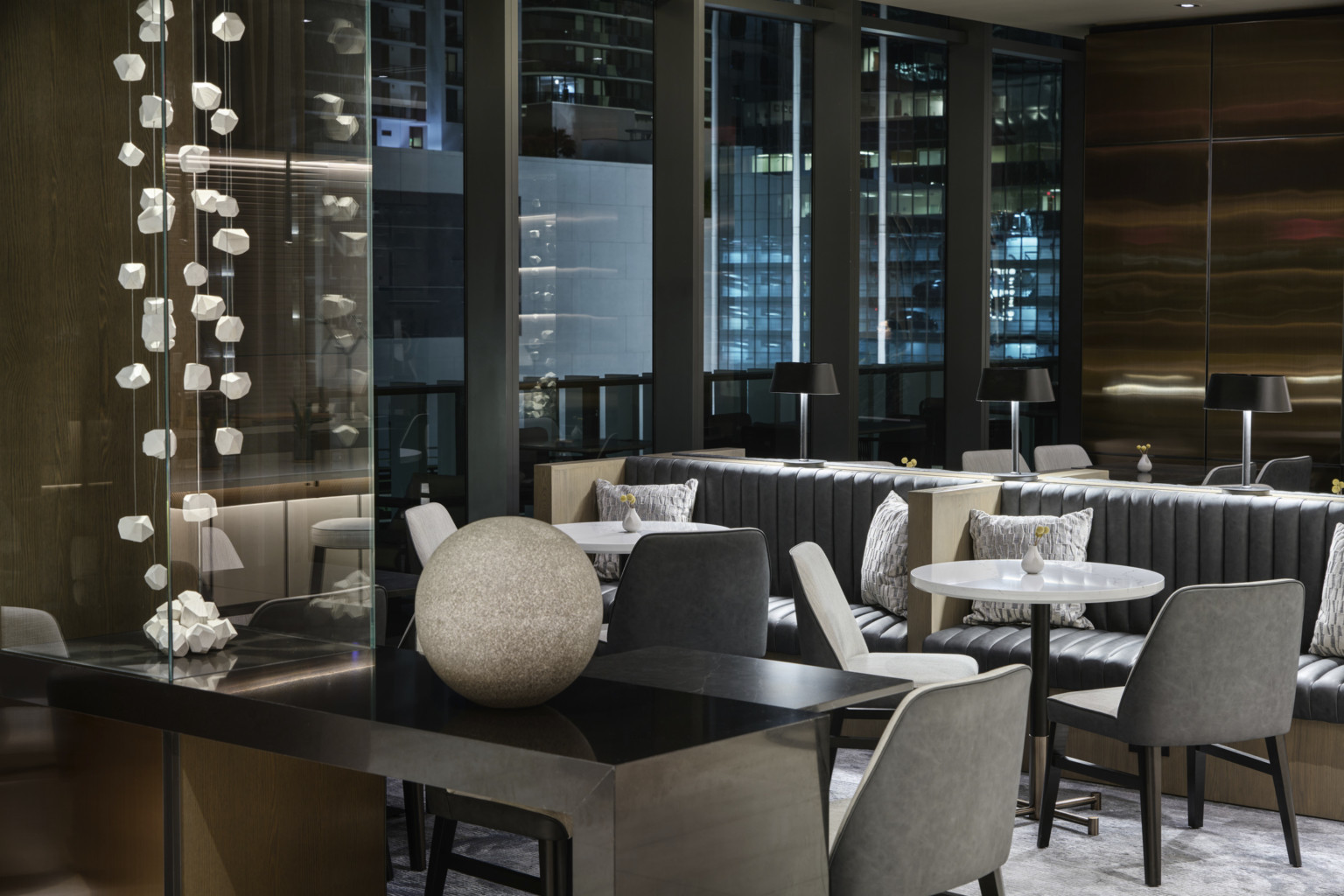 Intimate seating groups illuminated by the city lights, moments of artwork throughout the space, abstract hanging sculpture Intimate seating groups illuminated by the city lights, moments of artwork throughout the space, abstract hanging sculpture
