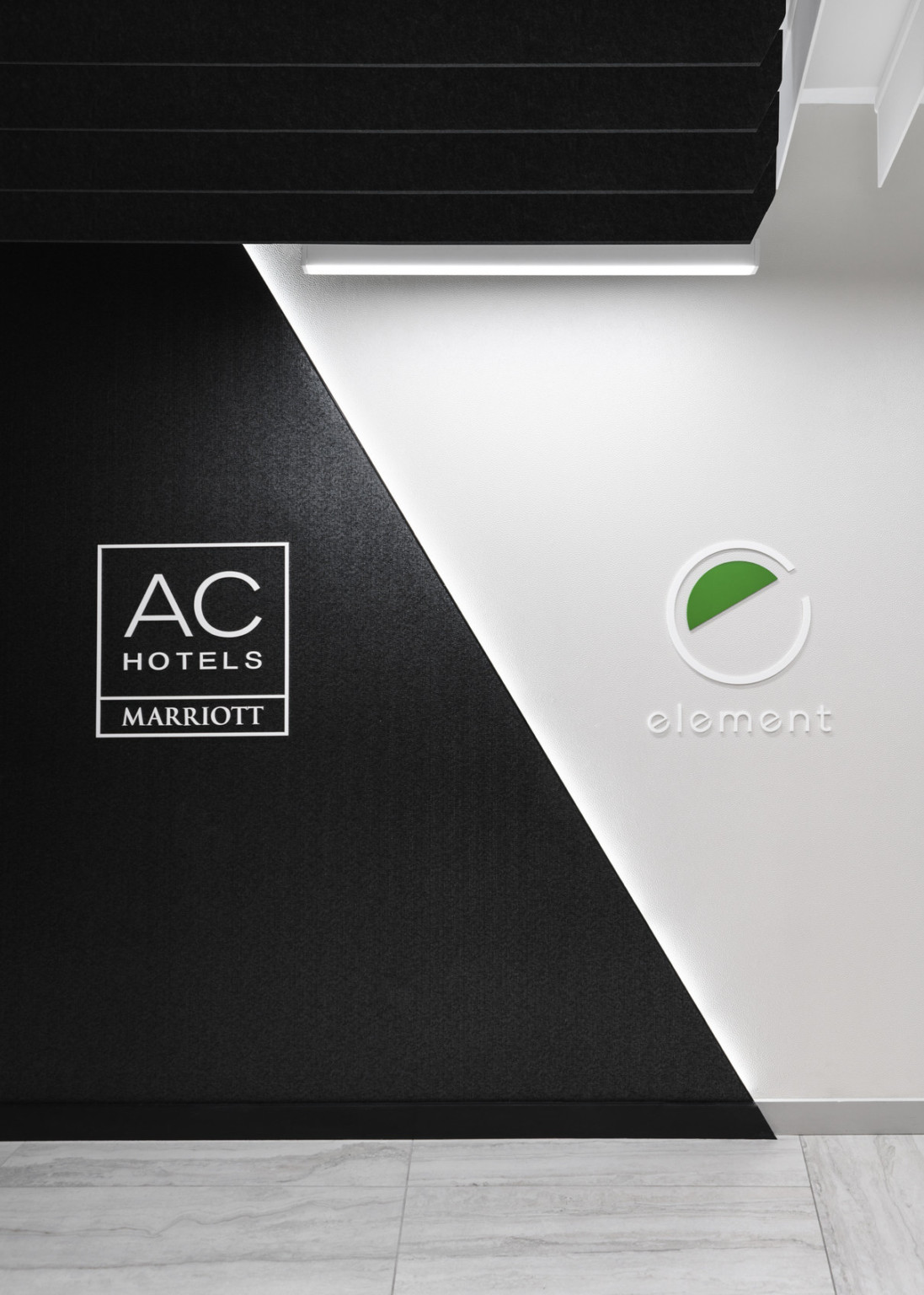 AC Hotel by Marriott & Element brand logos serve as wayfinding on black and white wall to direct guests to their destinations