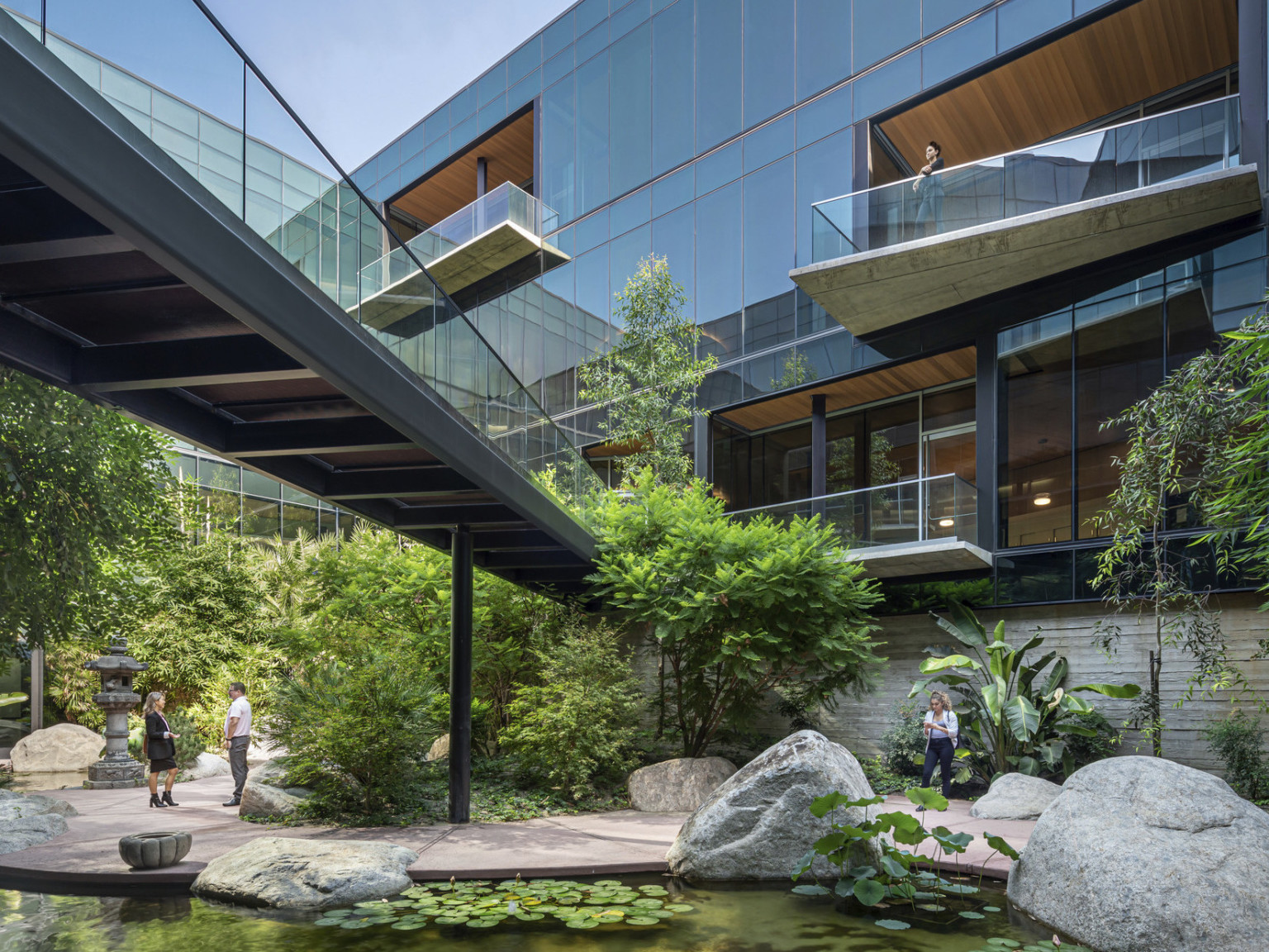 ESRI Campus front courtyard expansion. Angled overhanging balconies on a glass building with bridge over courtyard garden ESRI Campus front courtyard expansion. Angled overhanging balconies on a glass building with bridge over courtyard garden