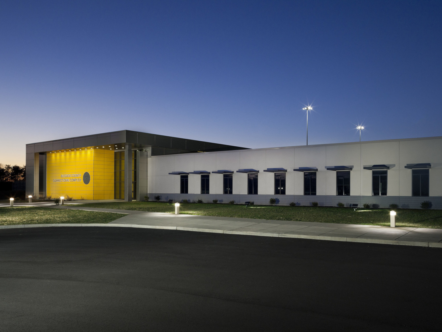 The Bledsoe County Correctional Complex exterior entryway viewed at night. Yellow accent wall is illuminated from above