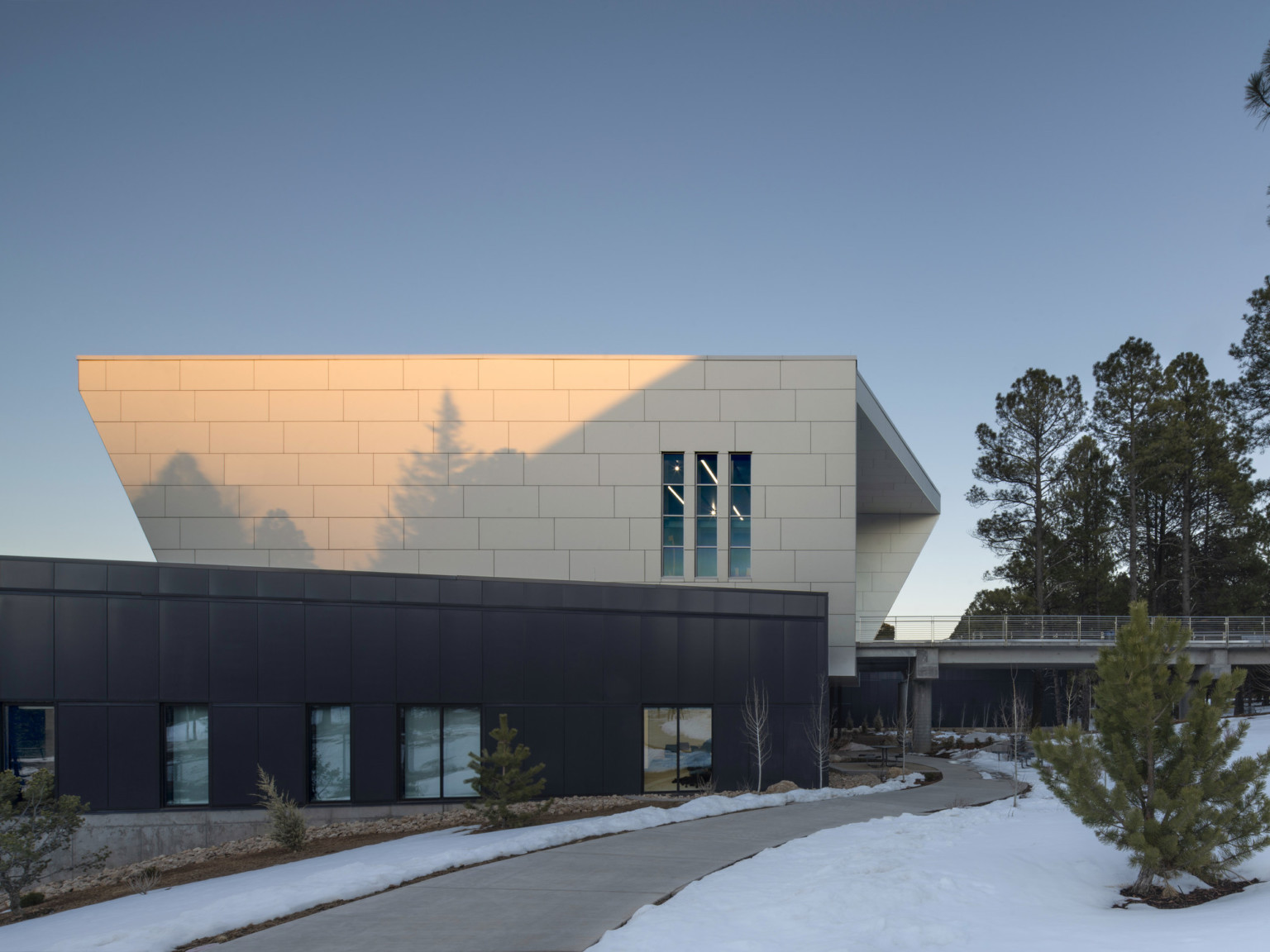 Northern Arizona University NAU student athlete center, elevated walkway with metal railings leading to white paneled wrap facade