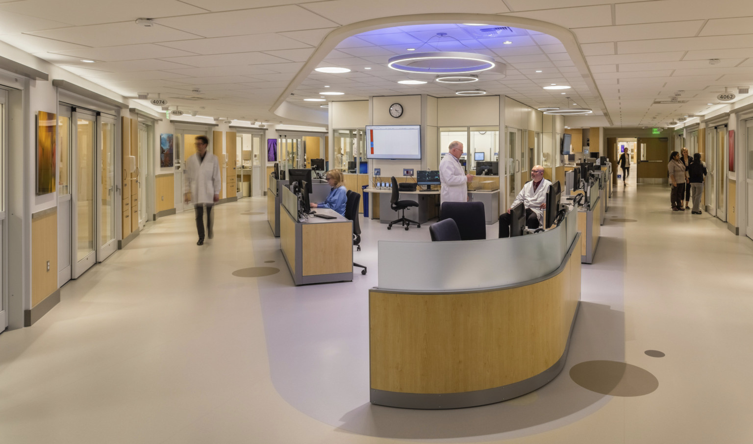 EvergreenHealth Progressive Care Unit with long desk wrapped around corner of hallway with blue and white accent lights above EvergreenHealth Progressive Care Unit with long desk wrapped around corner of hallway with blue and white accent lights above