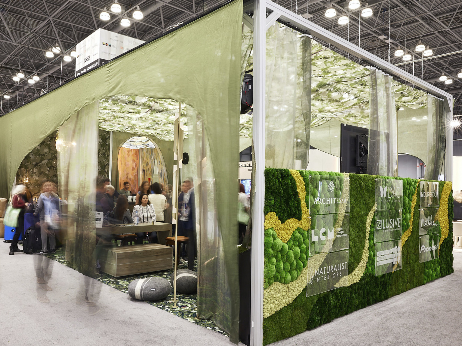 Exterior corner view of DLR Group's BDNY 2022 convention booth with textural living wall and green drapes around seating area Exterior corner view of DLR Group's BDNY 2022 convention booth with textural living wall and green drapes around seating area