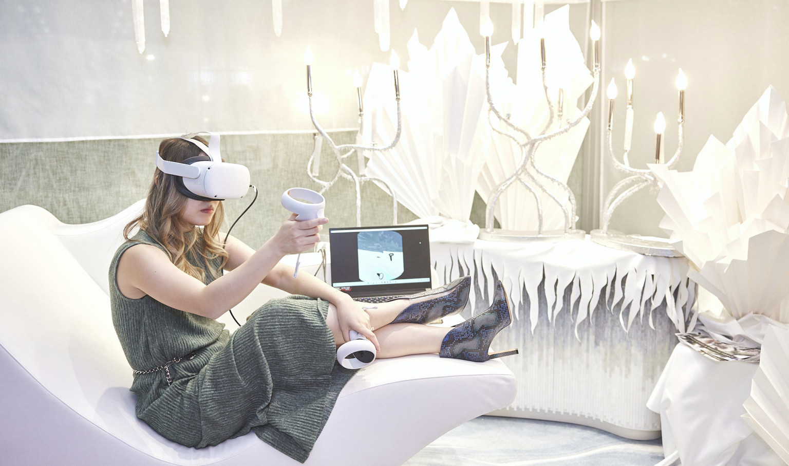 Woman uses virtual reality in all white wintery room with ice shard style sculptures and organically curving candelabra lights