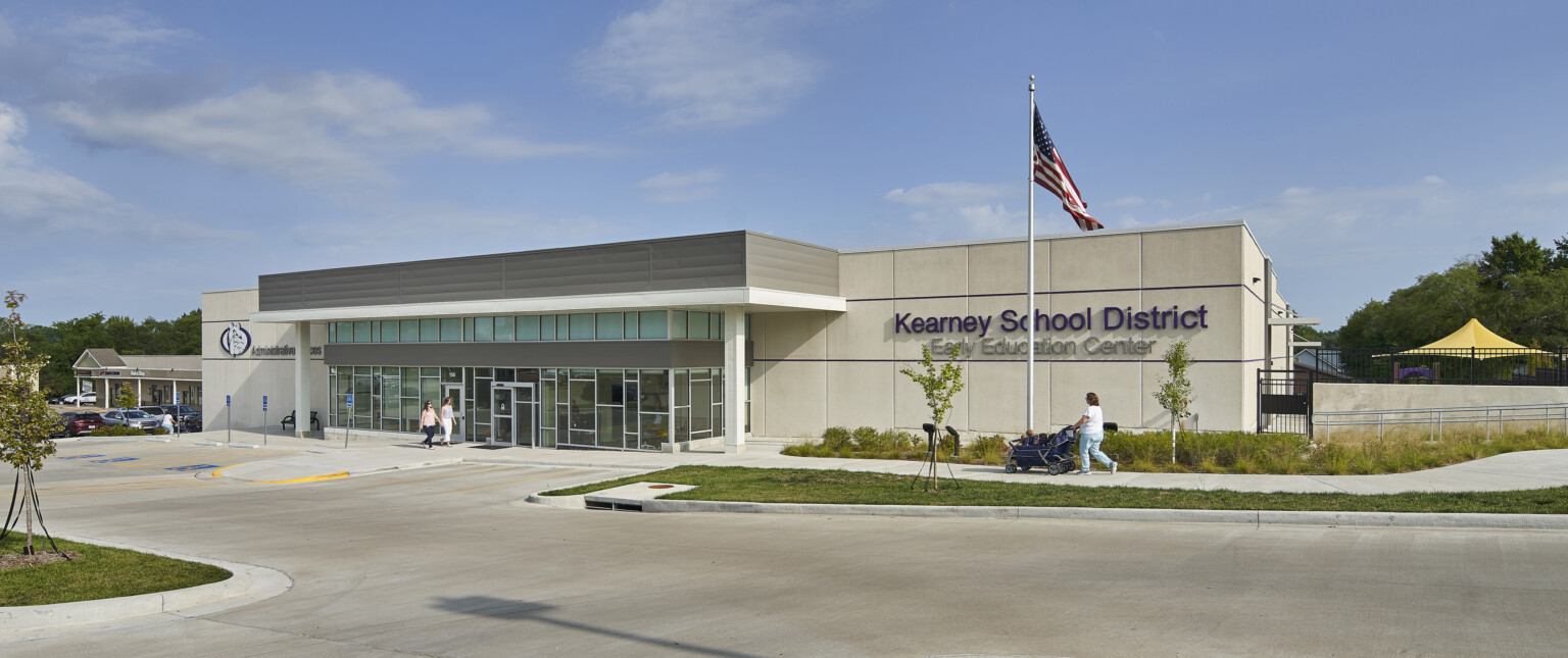 Exterior of grey concrete single story building with sign reading Kearney School District Early Education Center, glass entry