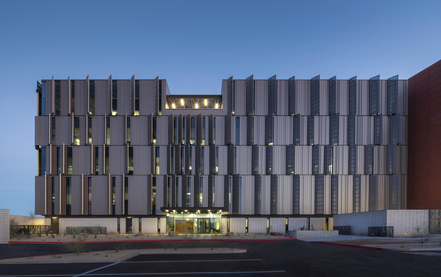 Dusk shot of Pinal County Attorney’s Offices, a serrated wrapped facade in alternating horizontal layers illuminated within