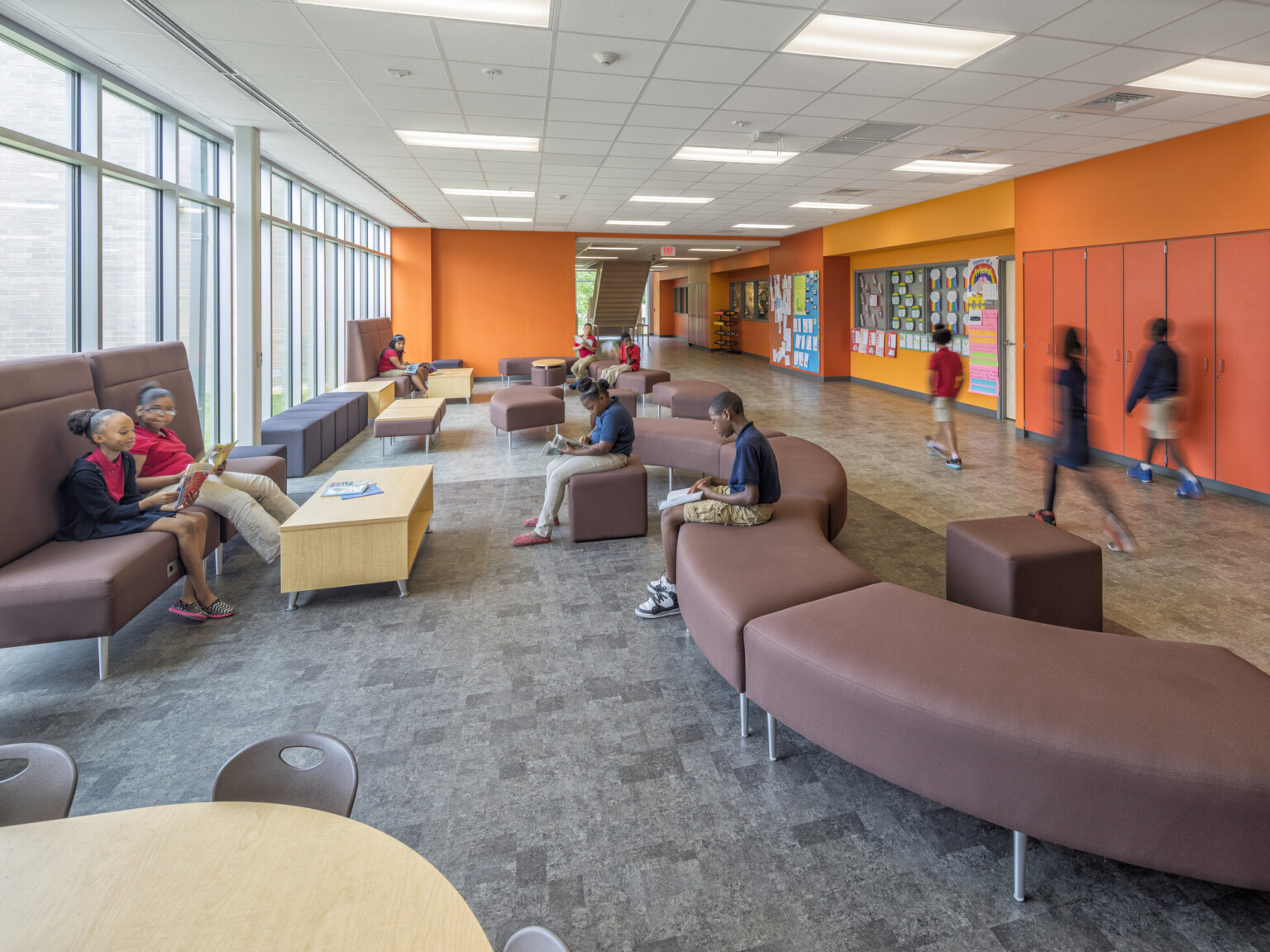 orange hallway in Boone Park Elementary School with mixed comfortable seating and floor to ceiling windows