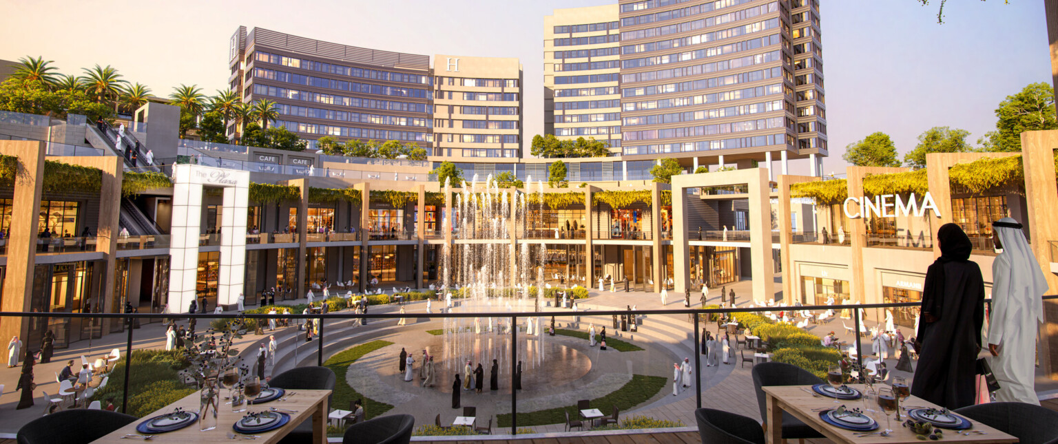Upper level of outdoor shopping center with pathway down, seen in the evening. Multiple planters and green roofs along path