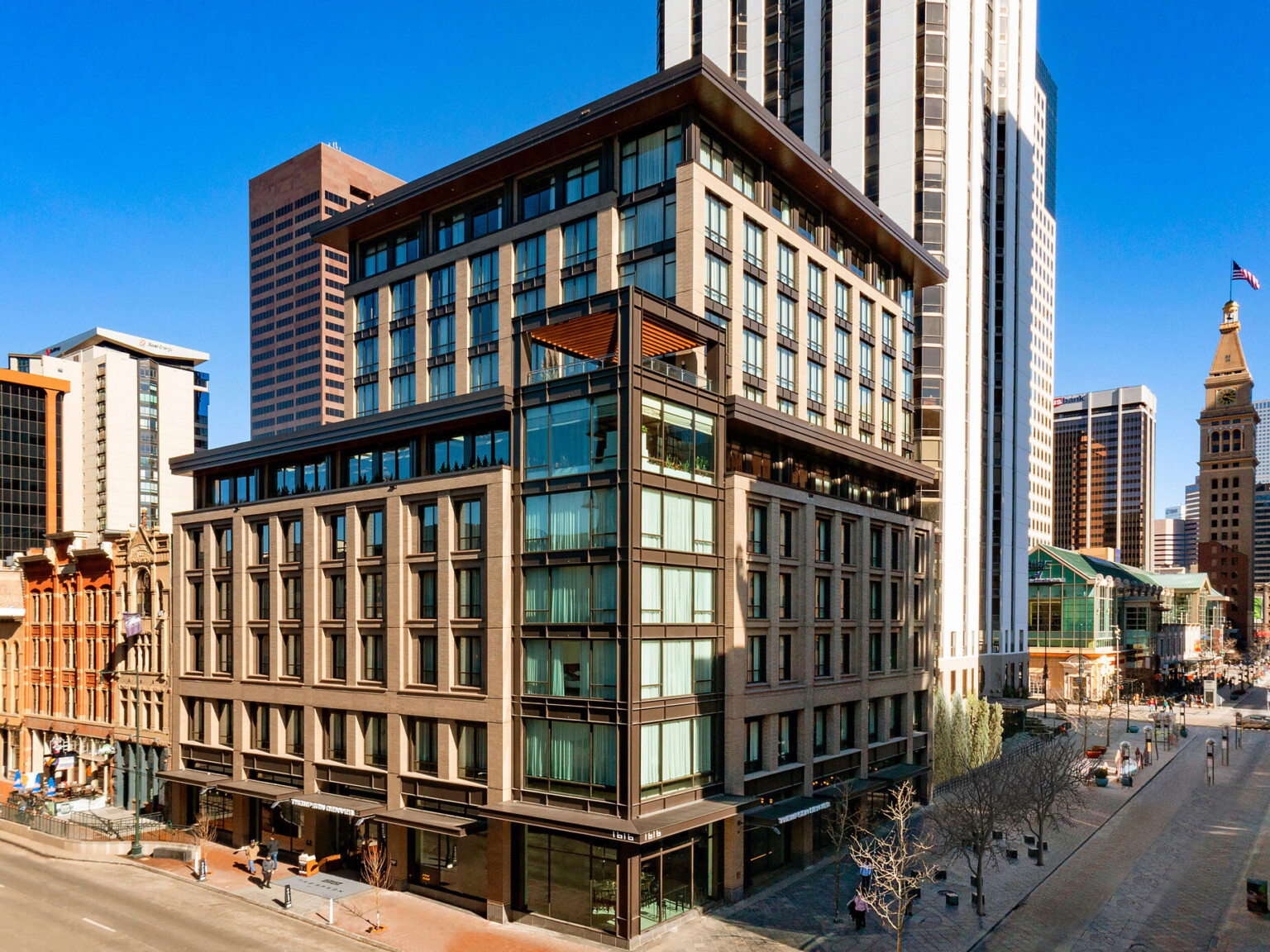 The Thompson Hotel Denver seen from corner with glass tower and stone facade on each side