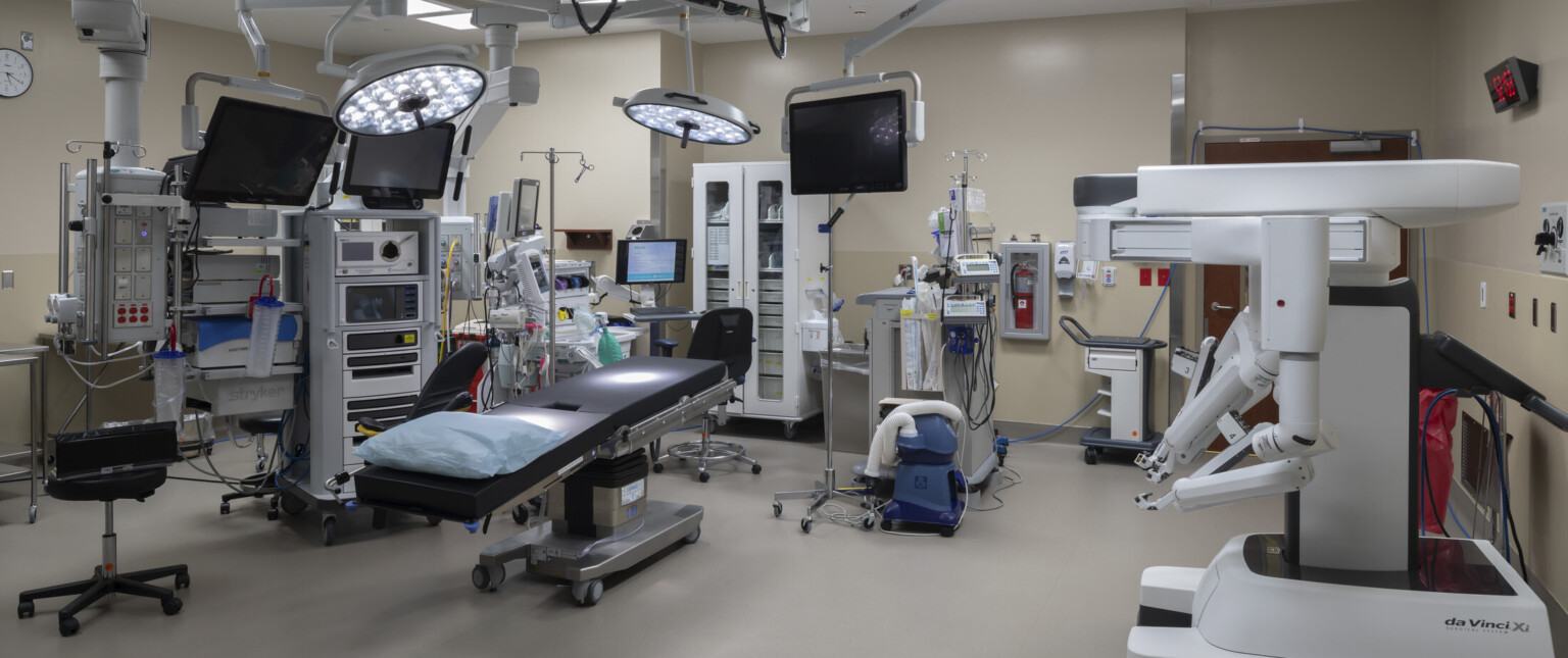 Operating room with equipment hanging over bed and along beige walls