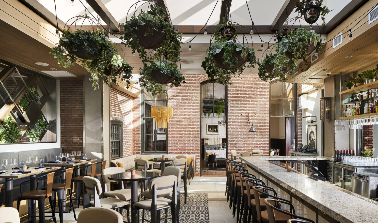 Brick walls, skylight, double-height windows, hanging plants, bar seating, in renovated firehouse